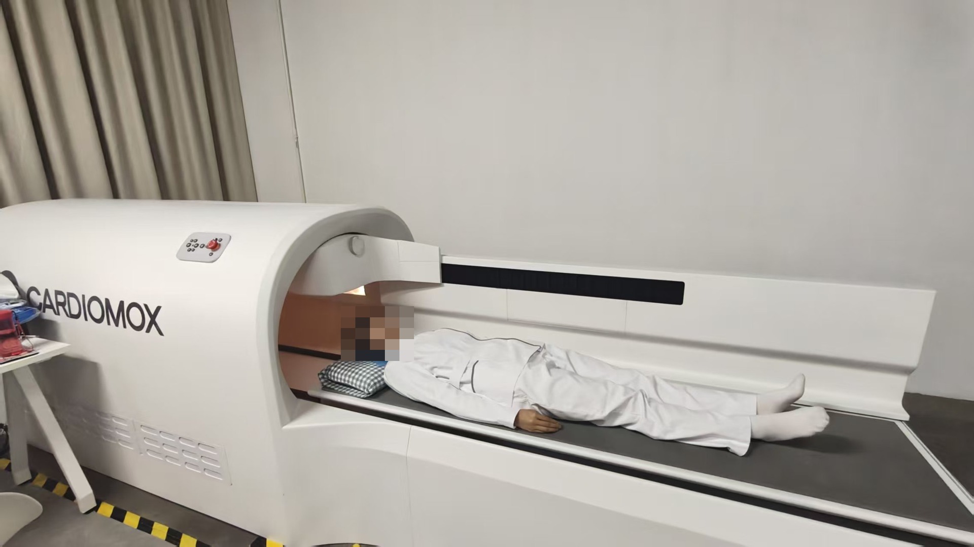 OPM clinical setting with magnetic shielding and a movable bed; the patient's face is pixelated